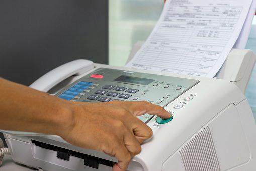 A person pushing a button on a fax machine