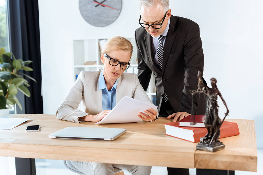 Employees in a law firm look at a printed document.