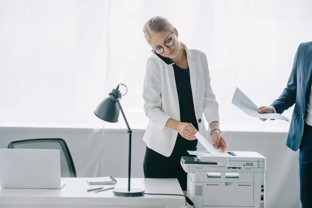 A woman using a Kyocera office printer.